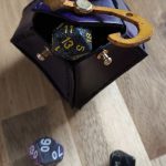 leather purple dice bag shaped like d10 (dice 10 sides) with the yellow sign as a design and bag closure mechanism.