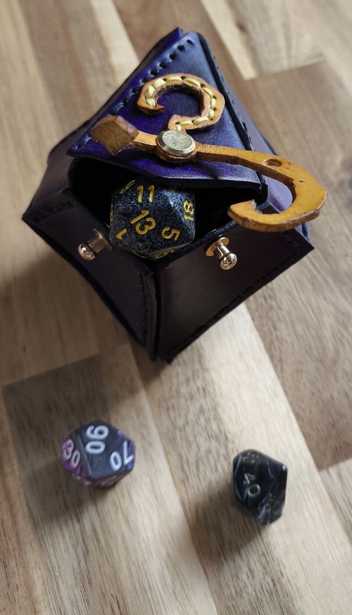 leather purple dice bag shaped like d10 (dice 10 sides) with the yellow sign as a design and bag closure mechanism.