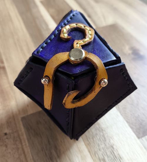 leather purple dice bag shaped like d10 (dice 10 sides) with the yellow sign as a design and bag closure mechanism.