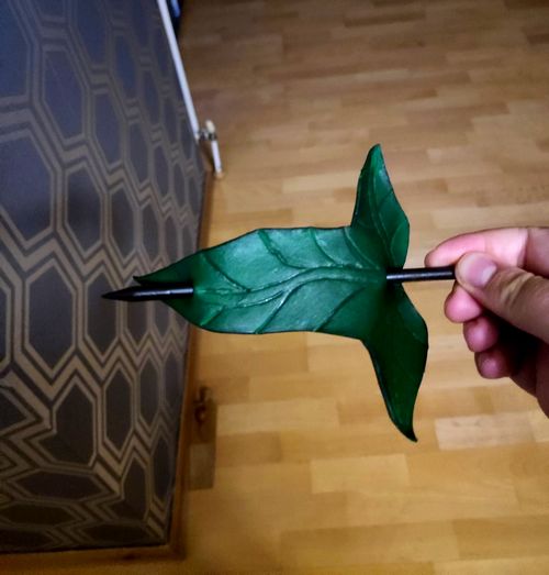 Crafted leather Lorien leaf hairpin in green with a black wooded stick.